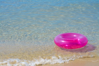 Bright inflatable ring on sandy beach near sea. Space for text
