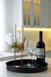 Photo of Pair of beautiful golden candlesticks and wine on white marble table in kitchen
