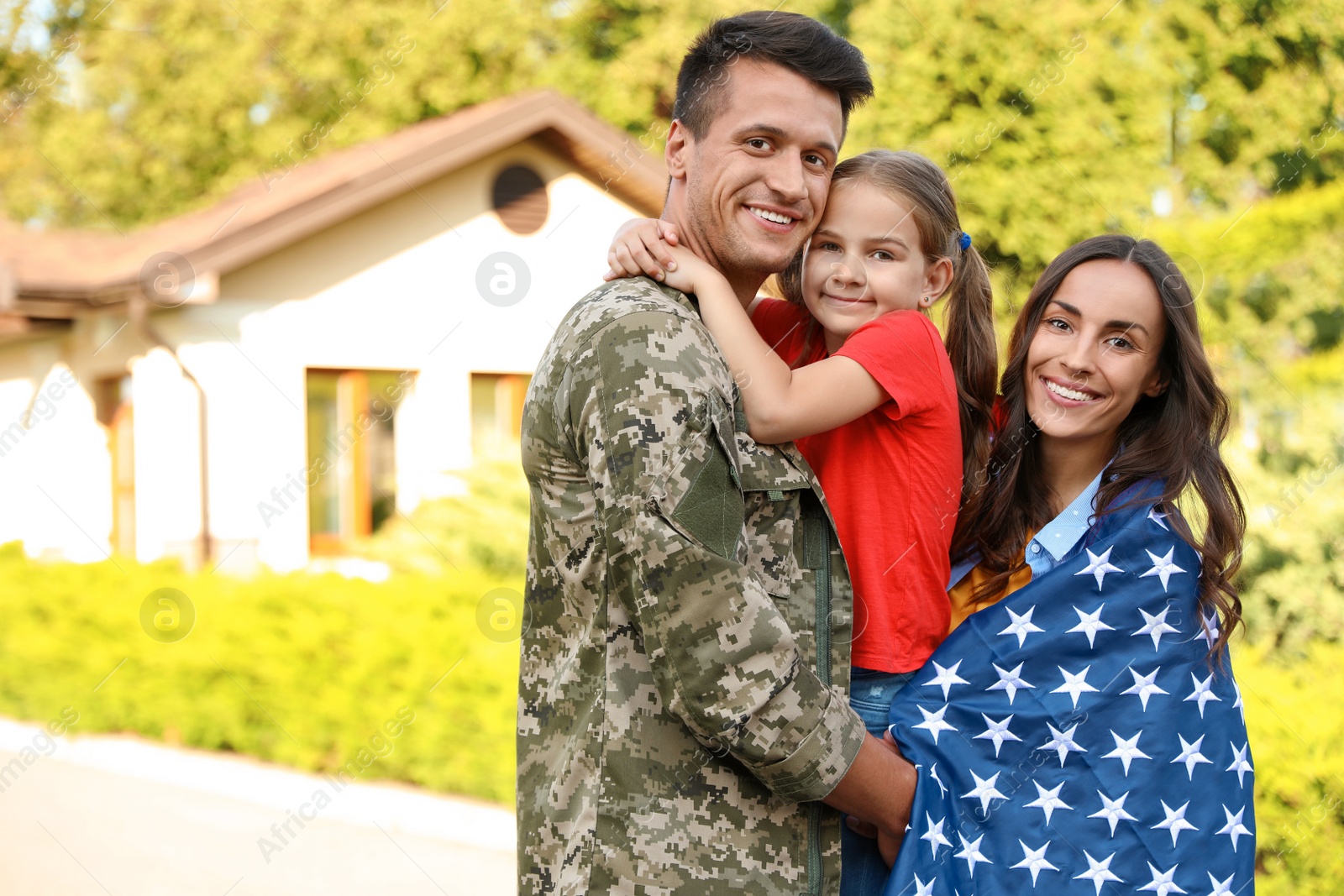 Photo of Man in military uniform and his family with American flag outdoors