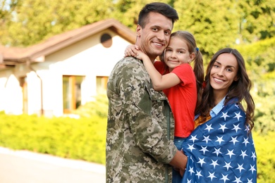 Photo of Man in military uniform and his family with American flag outdoors