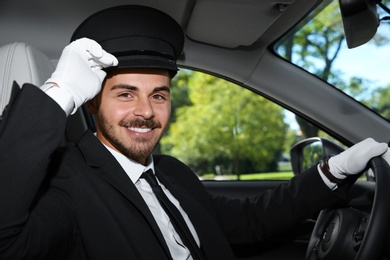 Photo of Young handsome driver in luxury car. Chauffeur service