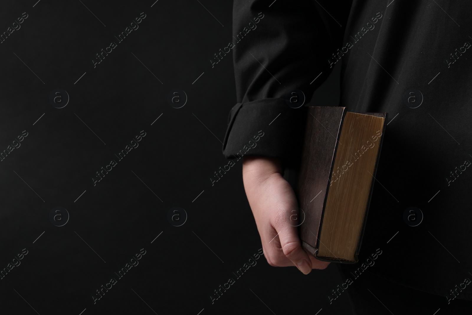 Photo of Woman with holy Bible on black background, closeup. Space for text