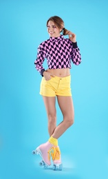 Young woman with retro roller skates on color background