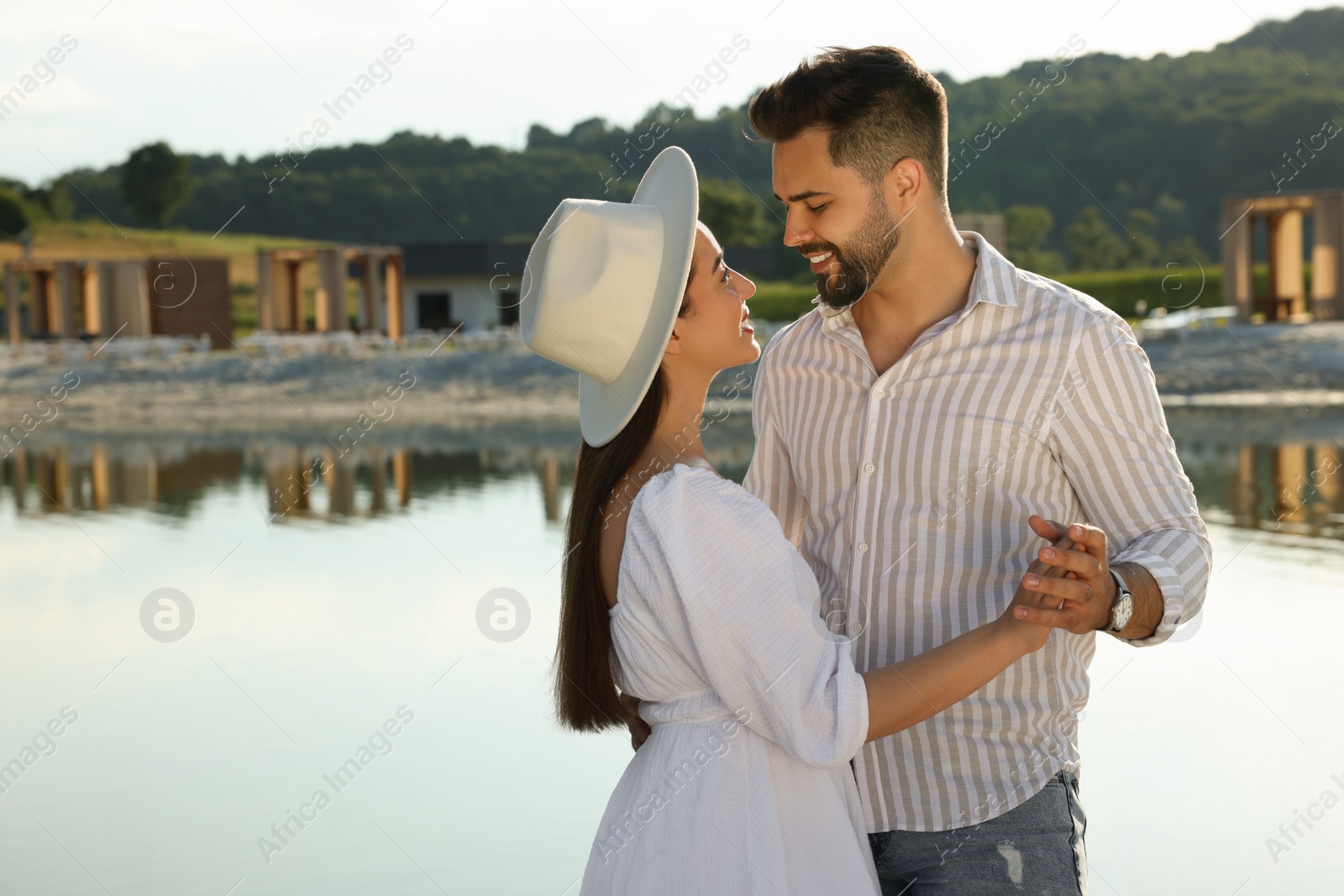 Photo of Romantic date. Beautiful couple spending time together near lake, space for text