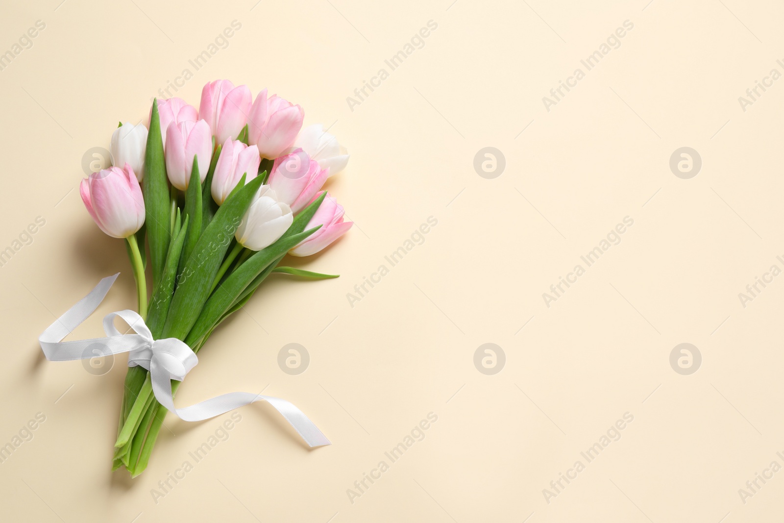 Photo of Beautiful pink spring tulips on beige background, top view. Space for text