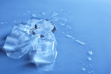 Photo of Transparent ice cubes on color mirror surface. Space for text