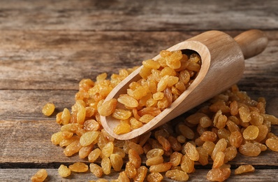 Photo of Scoop and raisins on wooden table. Dried fruit as healthy snack