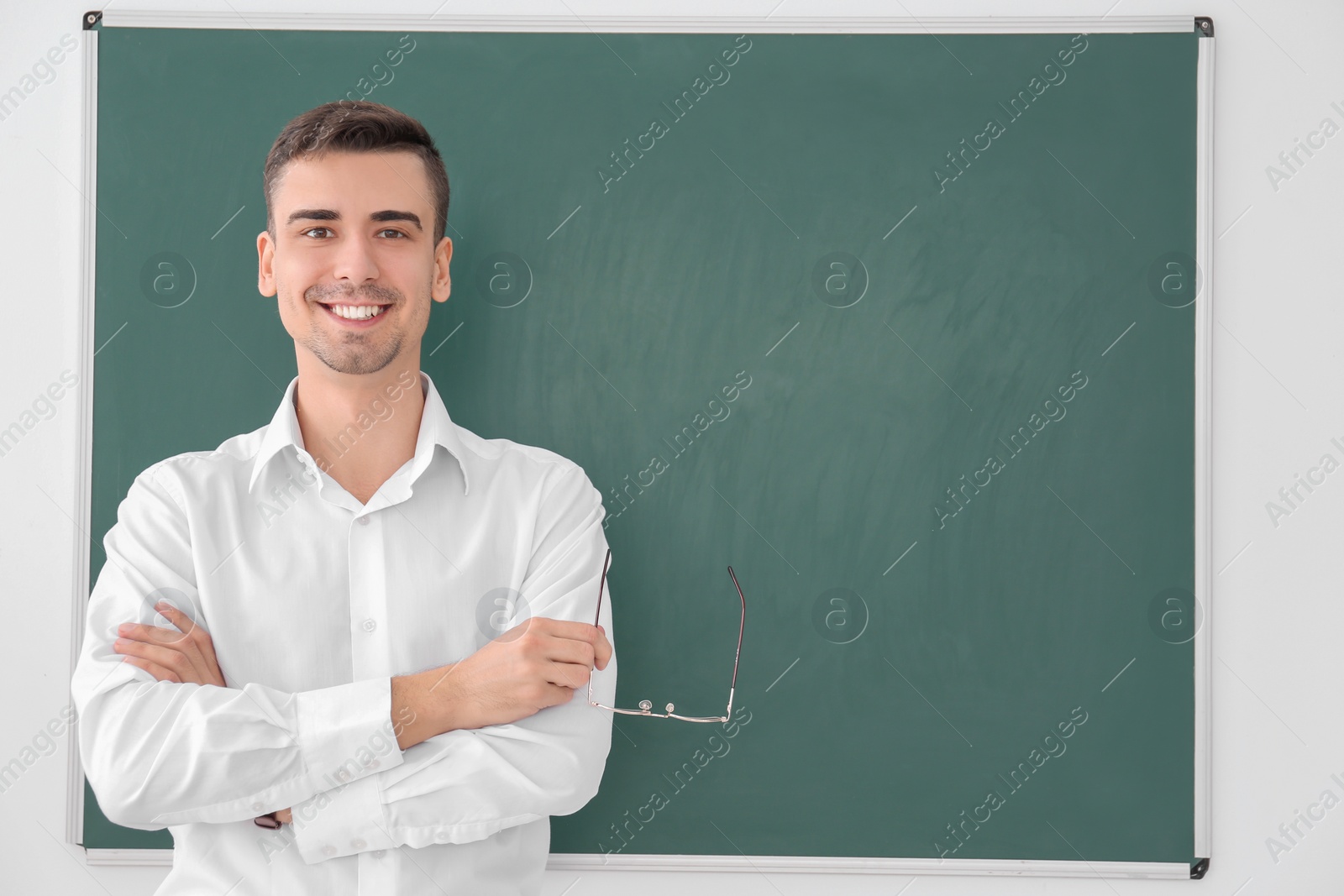 Photo of Young male teacher standing near blackboard on white background