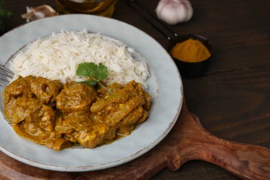 Photo of Delicious chicken curry with rice on wooden table, closeup