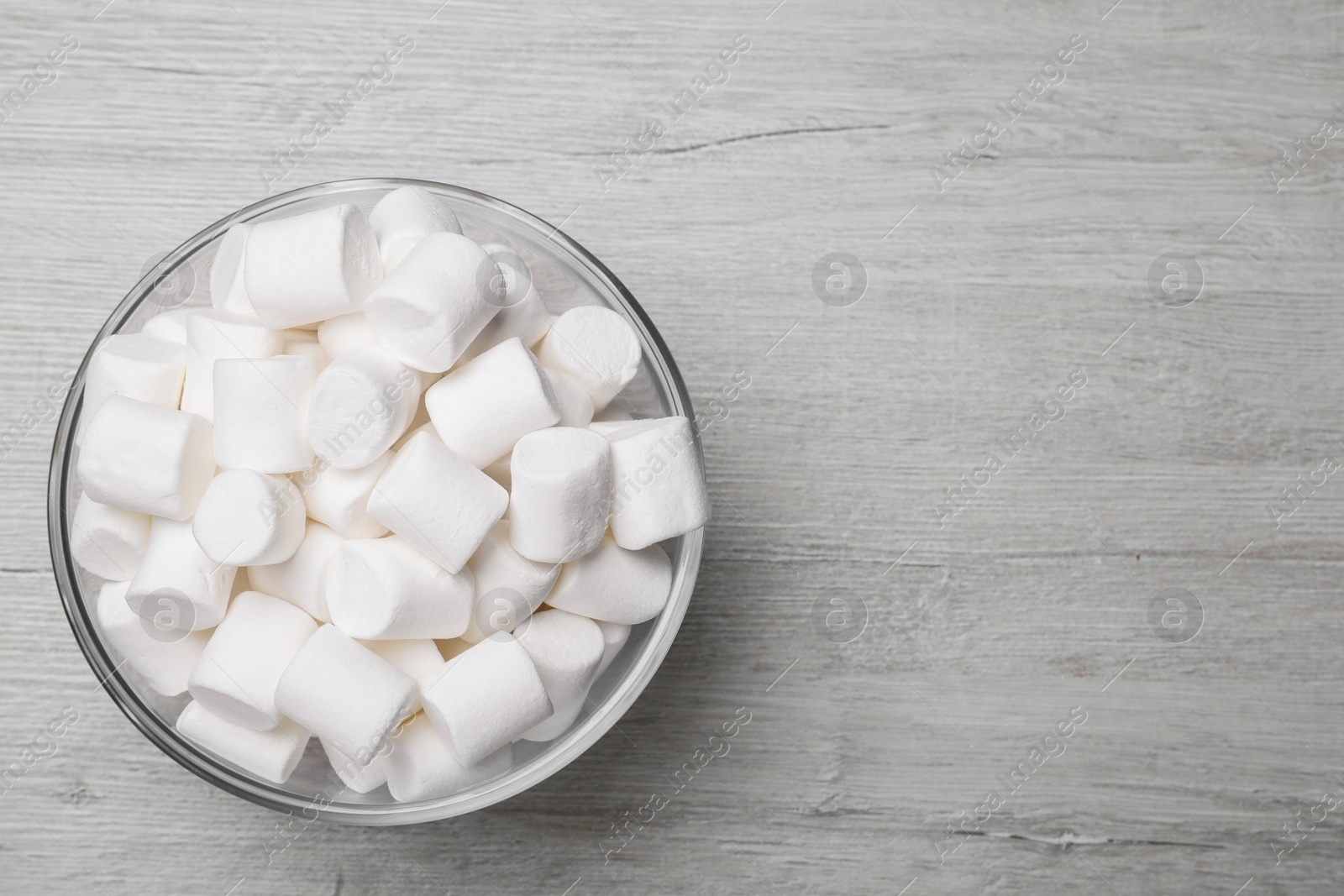 Photo of Delicious puffy marshmallows on wooden table, top view. Space for text