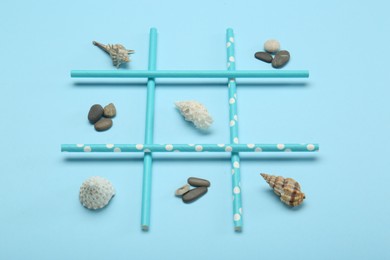 Photo of Tic tac toe game made with sea treasures on light blue background