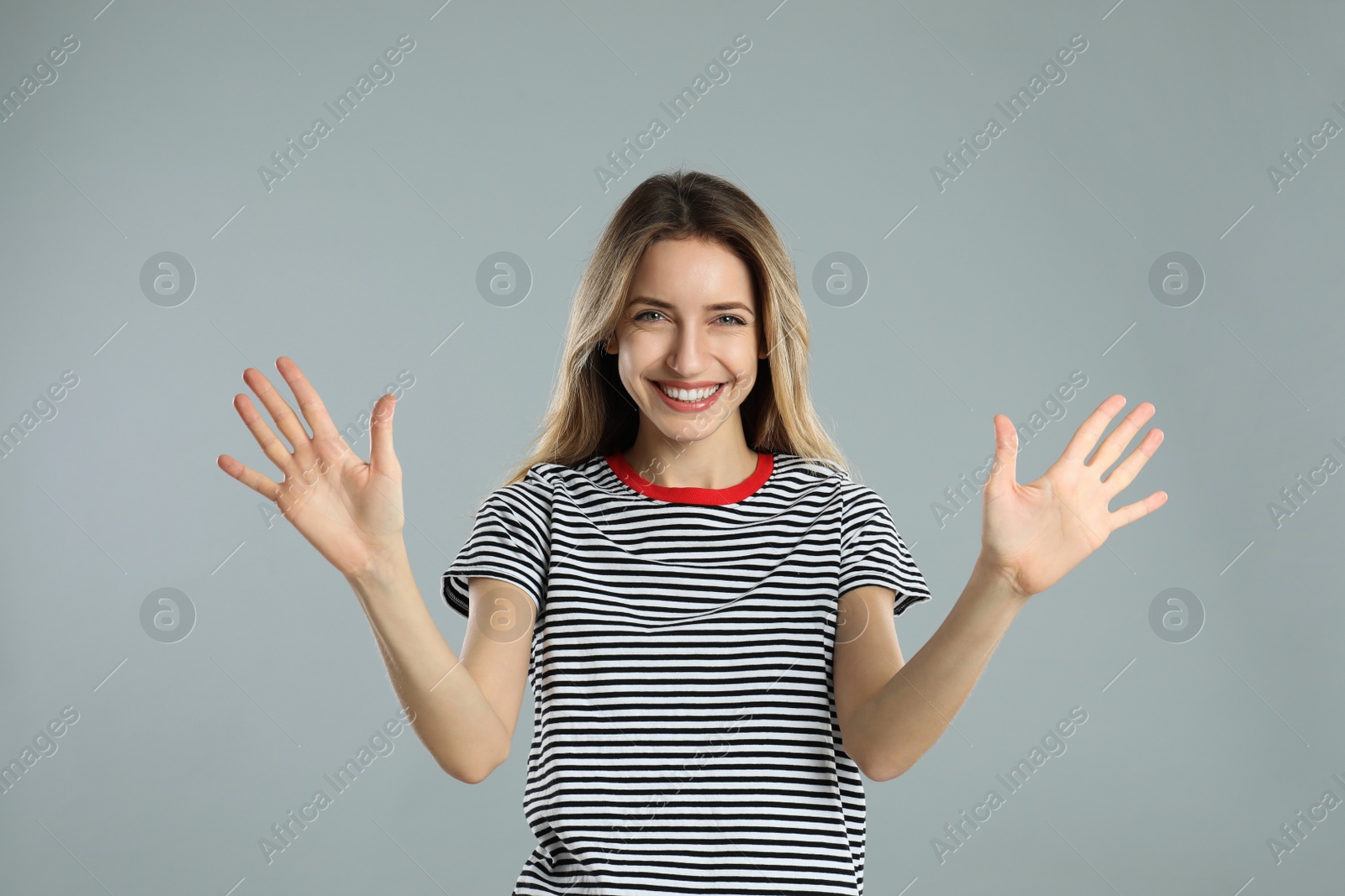 Photo of Woman showing number ten with her hands on light grey background