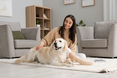 Happy woman with cute Labrador Retriever dog on floor at home. Adorable pet