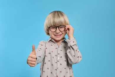 Photo of Cute little boy wearing glasses on light blue background