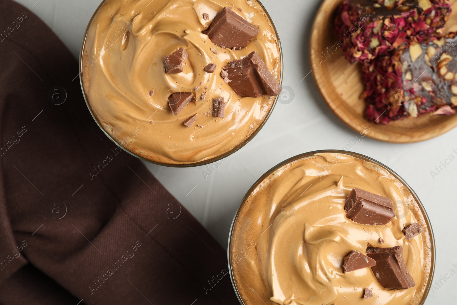 Photo of Glasses of delicious dalgona coffee with chocolate on light grey table, flat lay