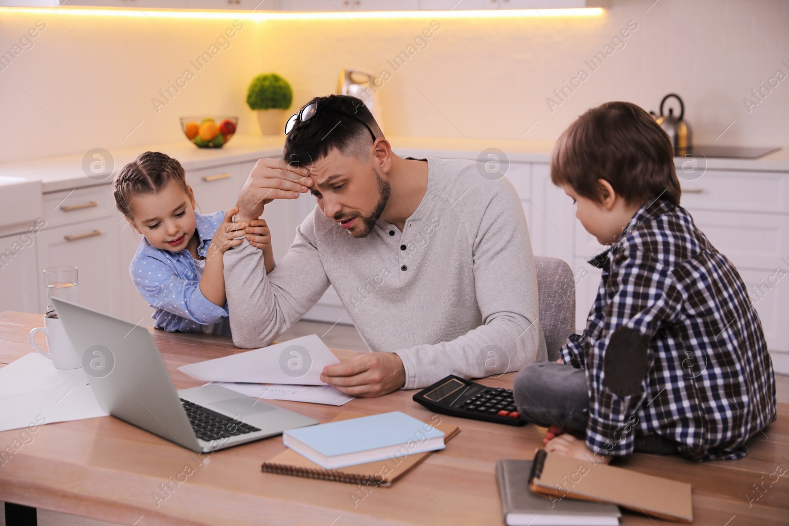 Photo of Overwhelmed man combining parenting and work at home