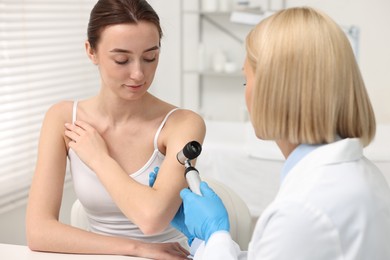 Photo of Dermatologist with dermatoscope examining patient in clinic