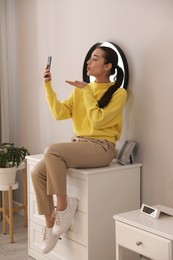 Young woman taking selfie at home in morning