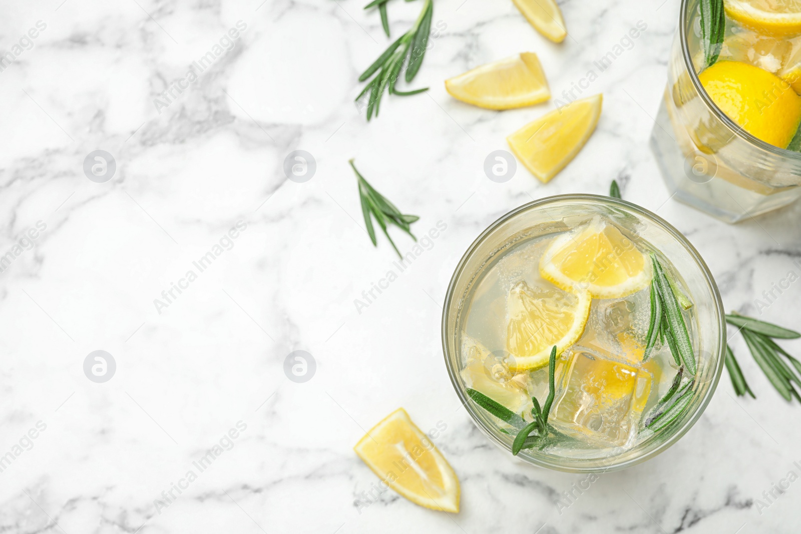 Photo of Glasses of refreshing lemonade on marble table, above view and space for text. Summer drink