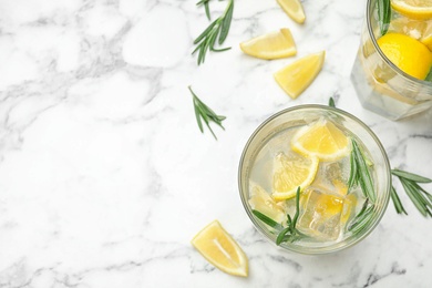 Photo of Glasses of refreshing lemonade on marble table, above view and space for text. Summer drink