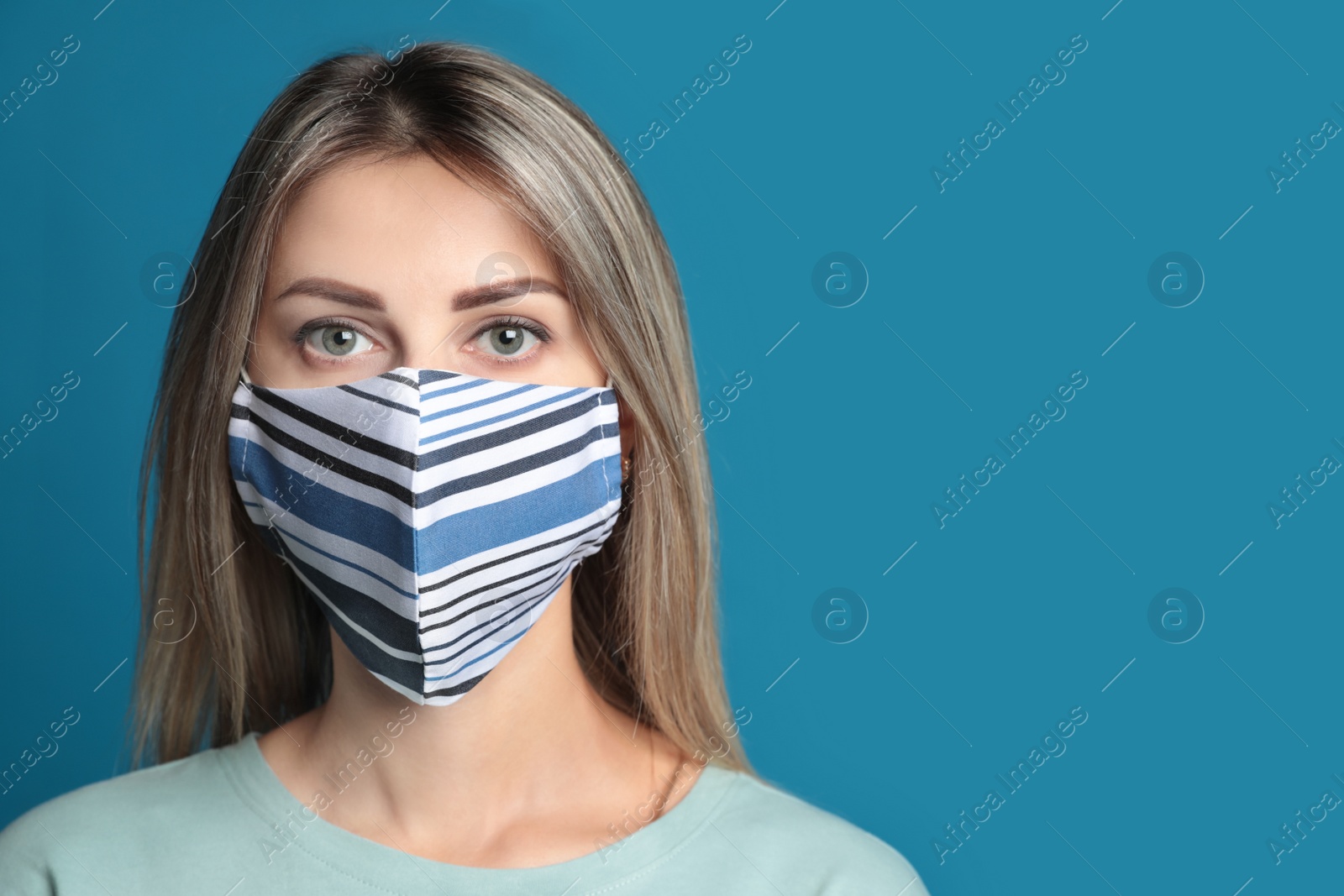 Photo of Young woman in protective face mask on blue background. Space for text