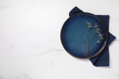 Elegant plate with twig and napkin on white marble table, top view. Space for text