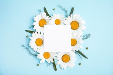 Beautiful floral composition with chamomile flowers and card on color background, top view