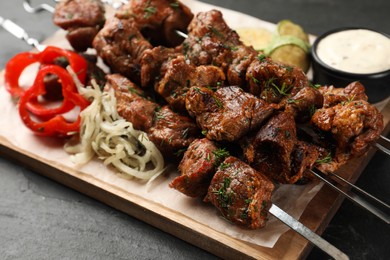 Metal skewers with delicious meat and vegetables served on black table, closeup