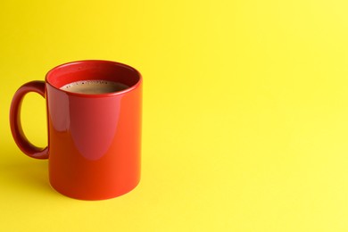 Photo of Red mug of freshly brewed hot coffee on yellow background, space for text