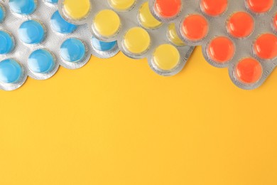 Photo of Blisters with cough drops on yellow background, flat lay. Space for text