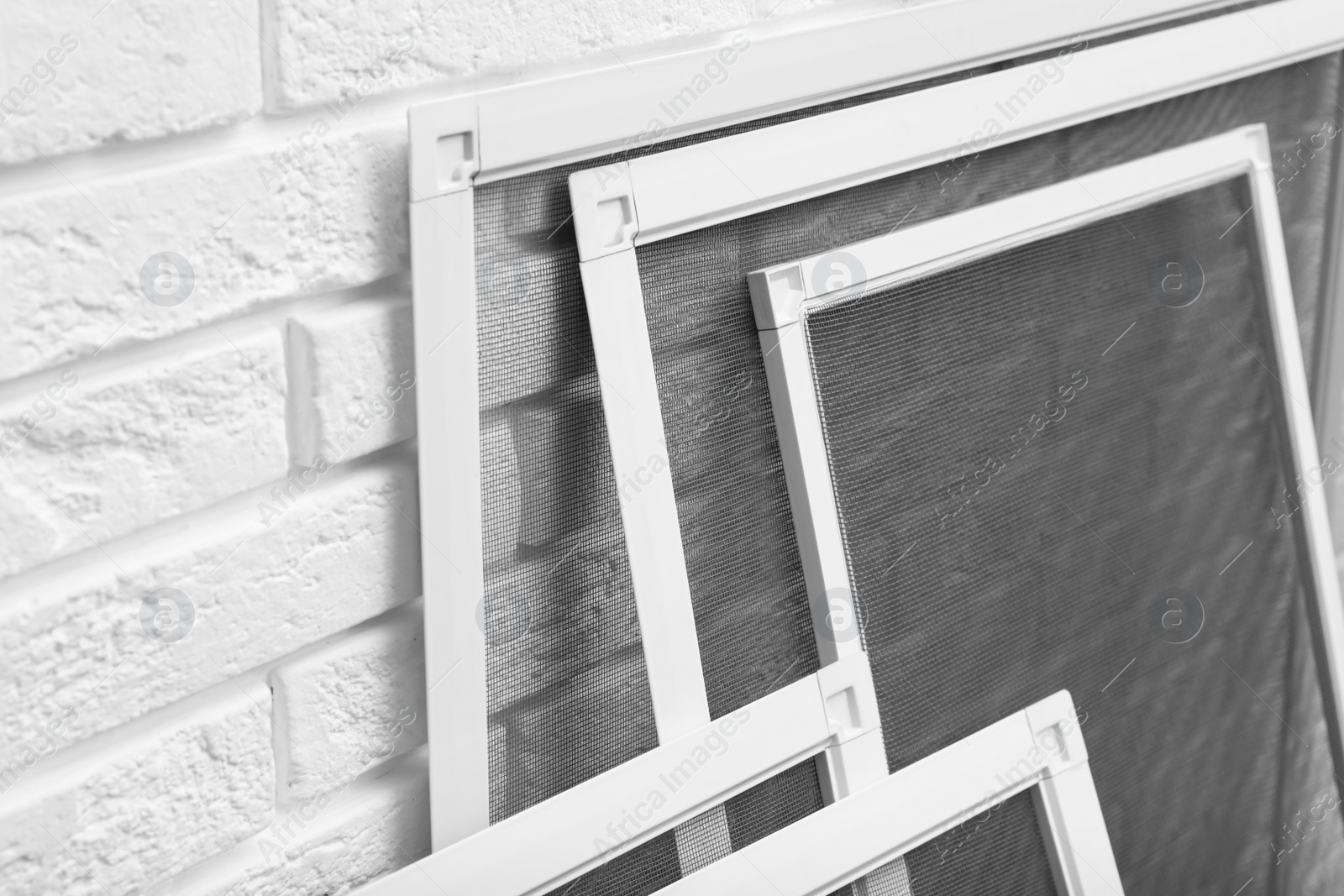 Photo of Set of window screens near white brick wall, closeup