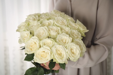 Photo of Woman holding luxury bouquet of fresh roses indoors, closeup