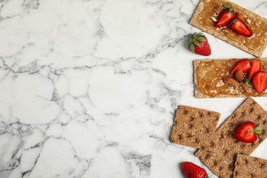 Photo of Fresh rye crispbreads with jam, strawberries and almonds on white marble table, flat lay. Space for text