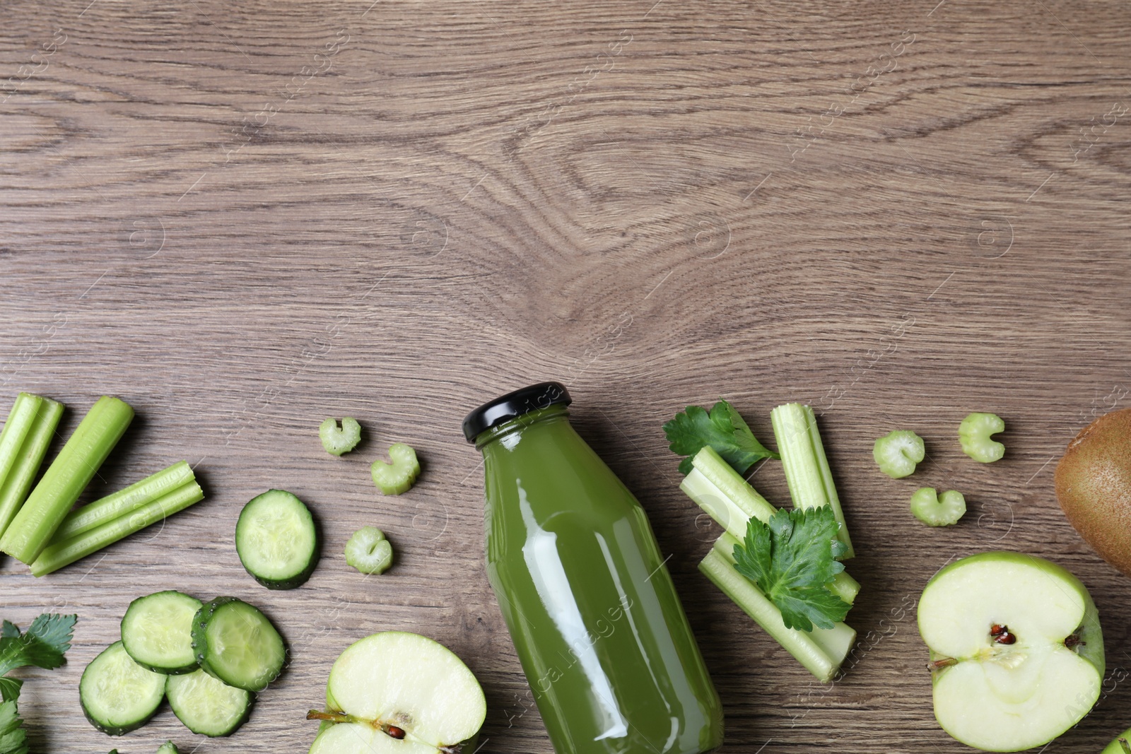 Photo of Glass bottle of celery juice and fresh ingredients on wooden table, flat lay. Space for text