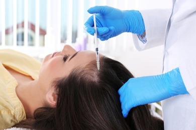 Photo of Young woman with hair loss problem receiving injection in salon