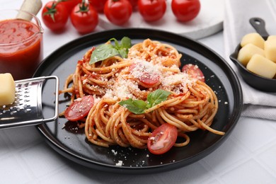 Tasty pasta with tomato sauce, cheese and basil on white tiled table