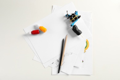 Photo of Composition with sheets of paper and tattoo machine on white background, top view
