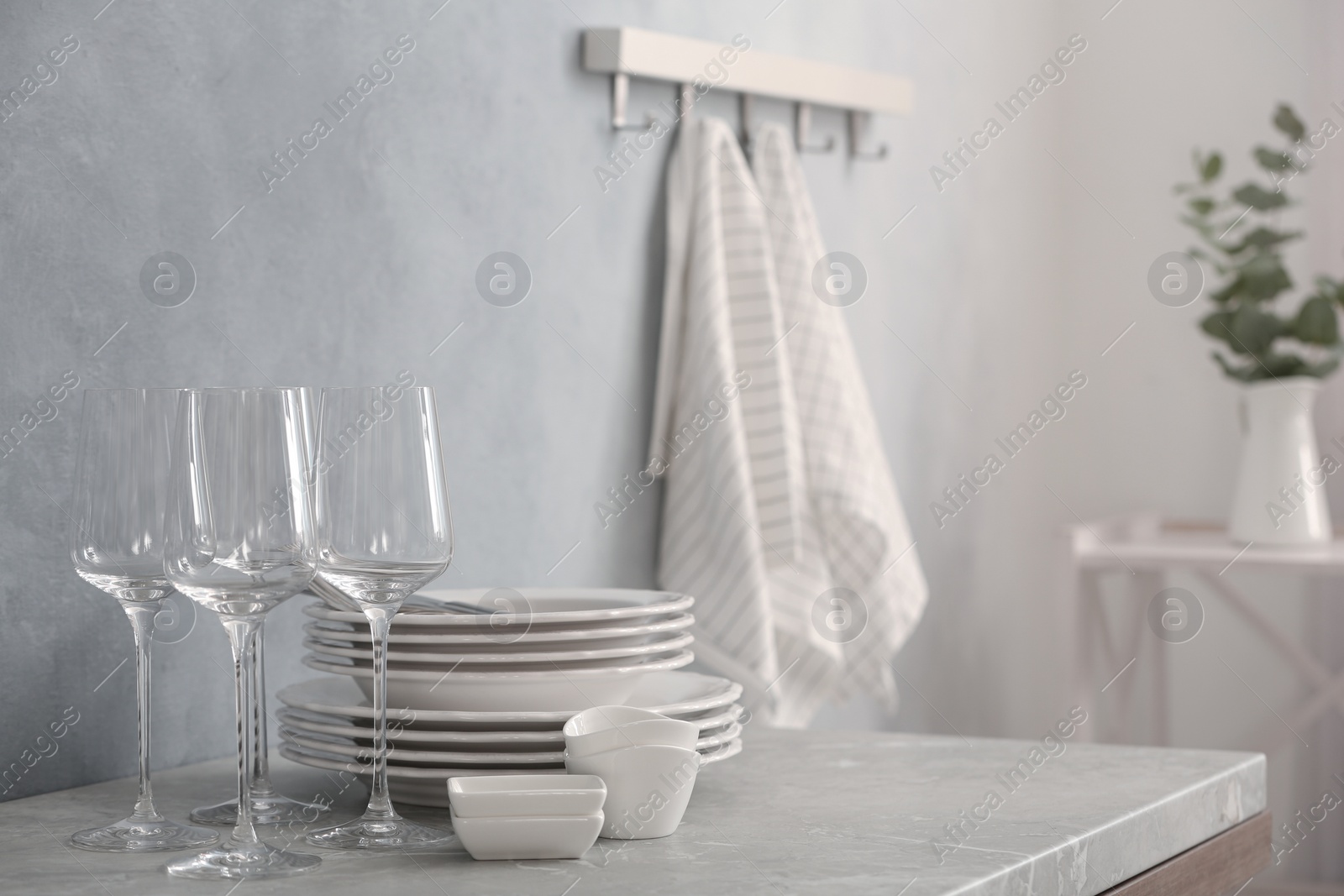 Photo of Set of clean dishware and wineglasses on grey table indoors. Space for text