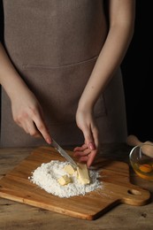 Photo of Woman cutting fresh butter at wooden table, closeup