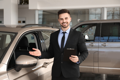 Salesman with clipboard near car in dealership