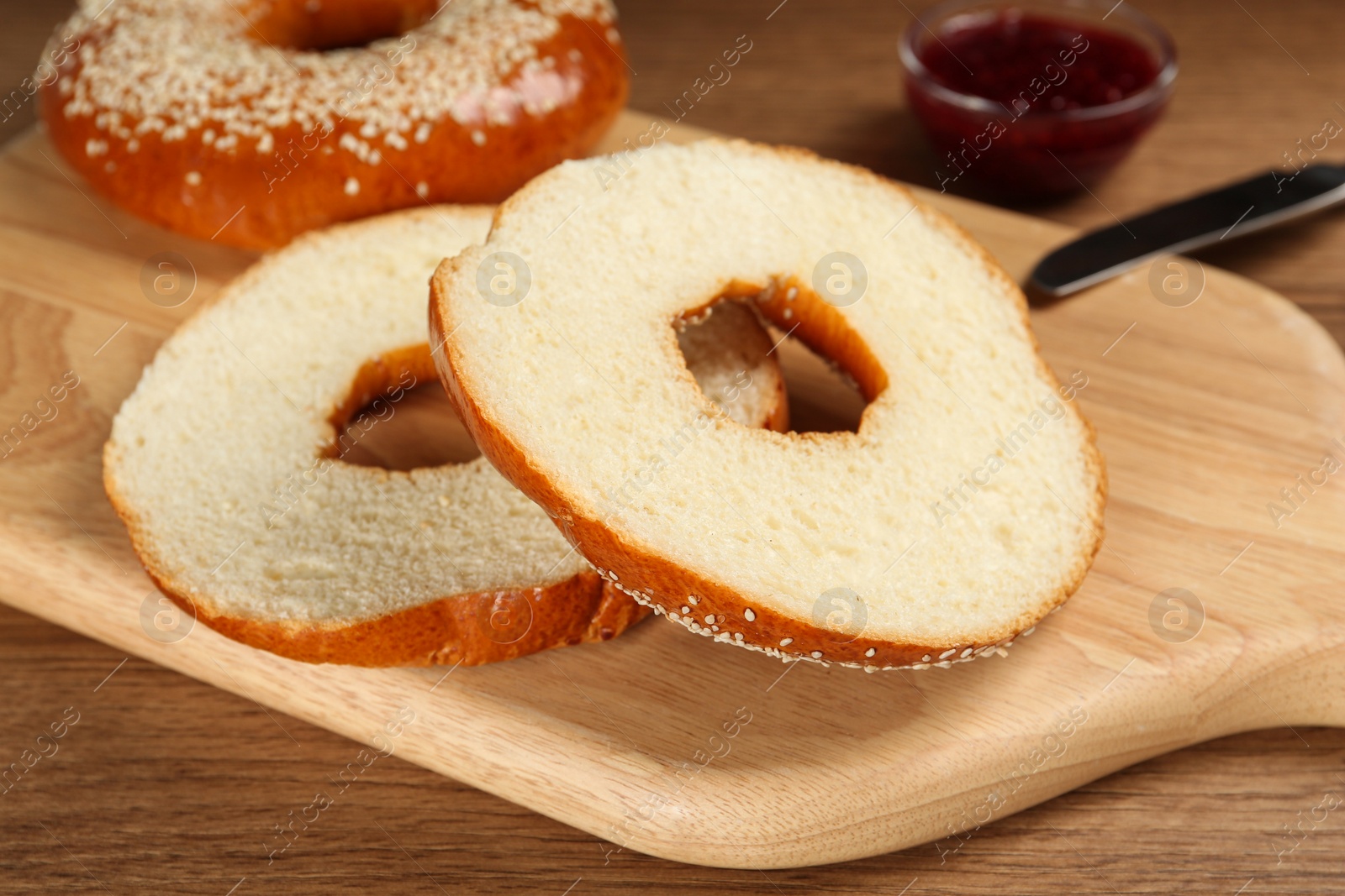 Photo of Delicious fresh bagels with sesame seeds on wooden table, closeup