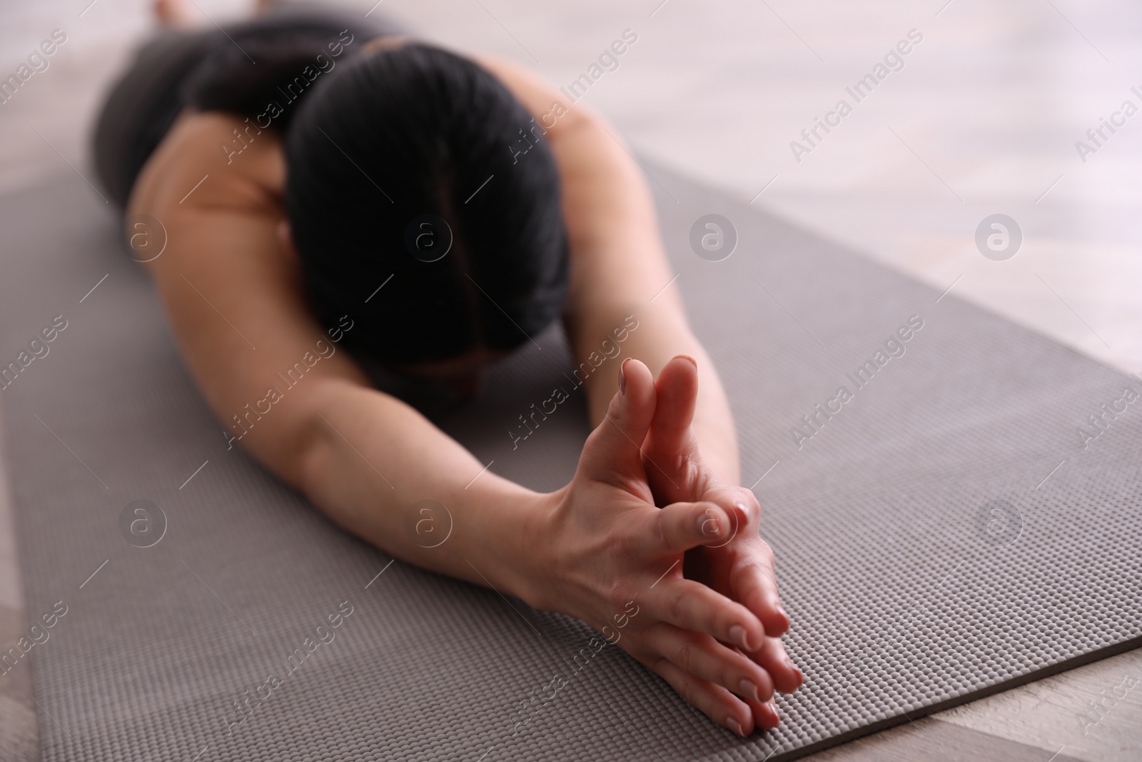 Photo of Young woman practicing extended child's asana in yoga studio, closeup. Utthita Balasana pose