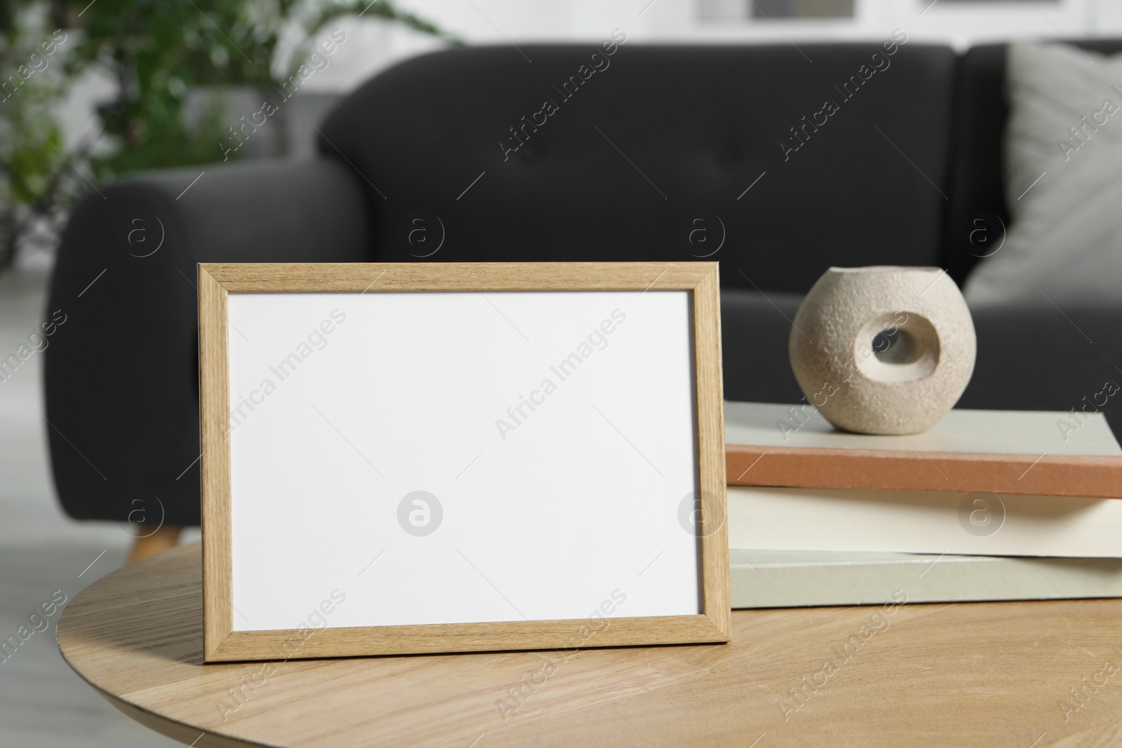 Photo of Empty square frame and books on coffee table indoors