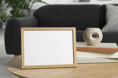 Empty square frame and books on coffee table indoors