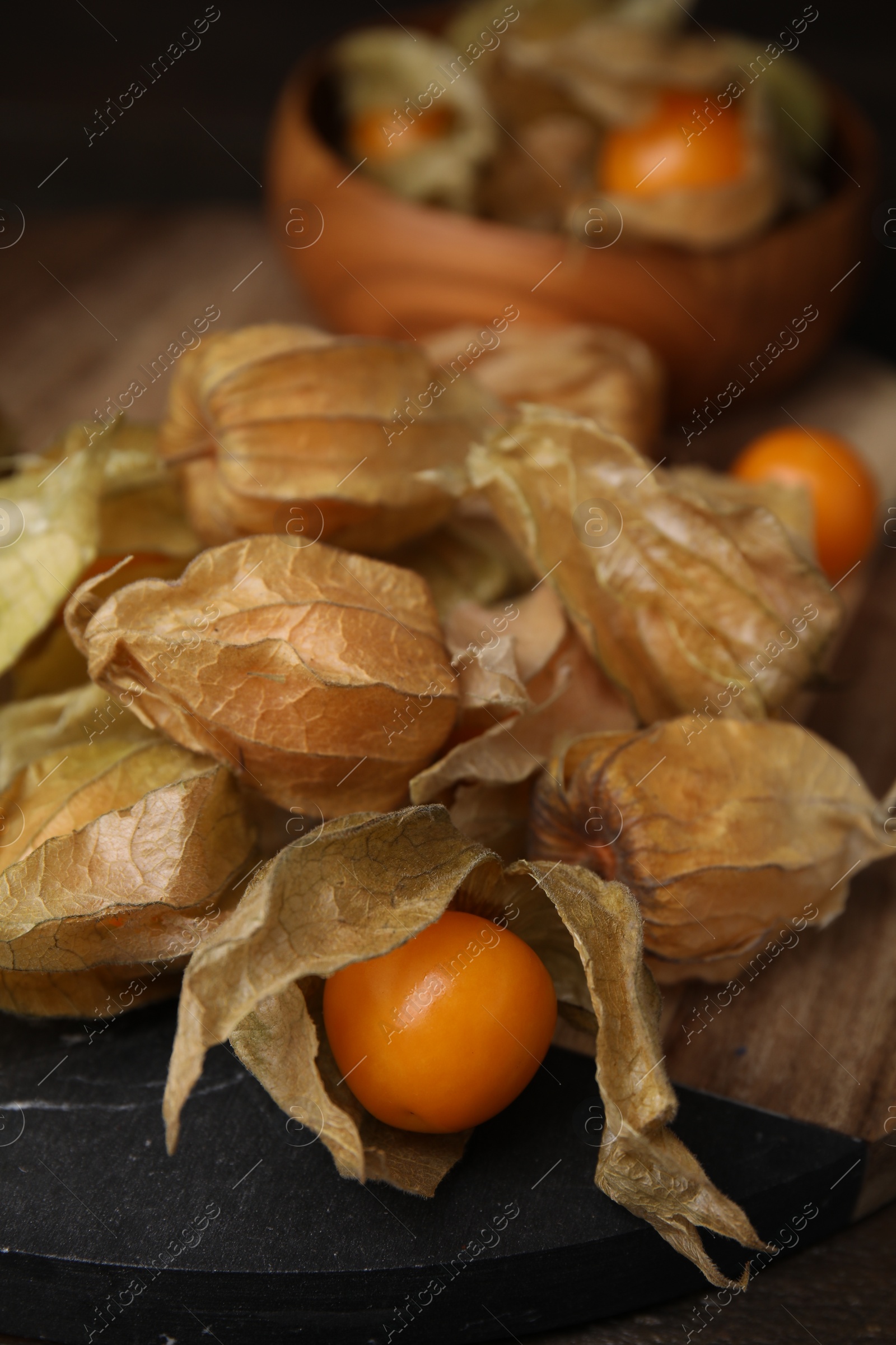 Photo of Ripe physalis fruits with calyxes on wooden table, closeup