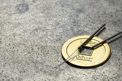 Acupuncture needles and Chinese coin on grey textured table, closeup. Space for text