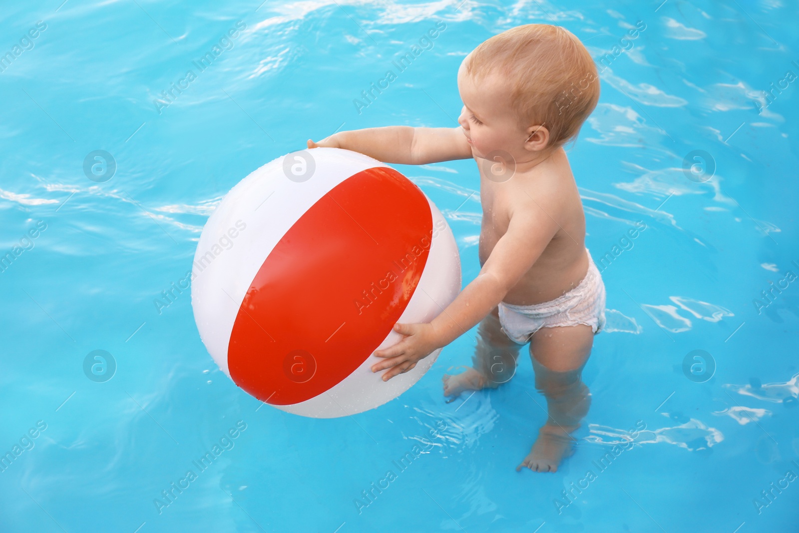 Photo of Little baby playing with inflatable ball in outdoor swimming pool. Dangerous situation