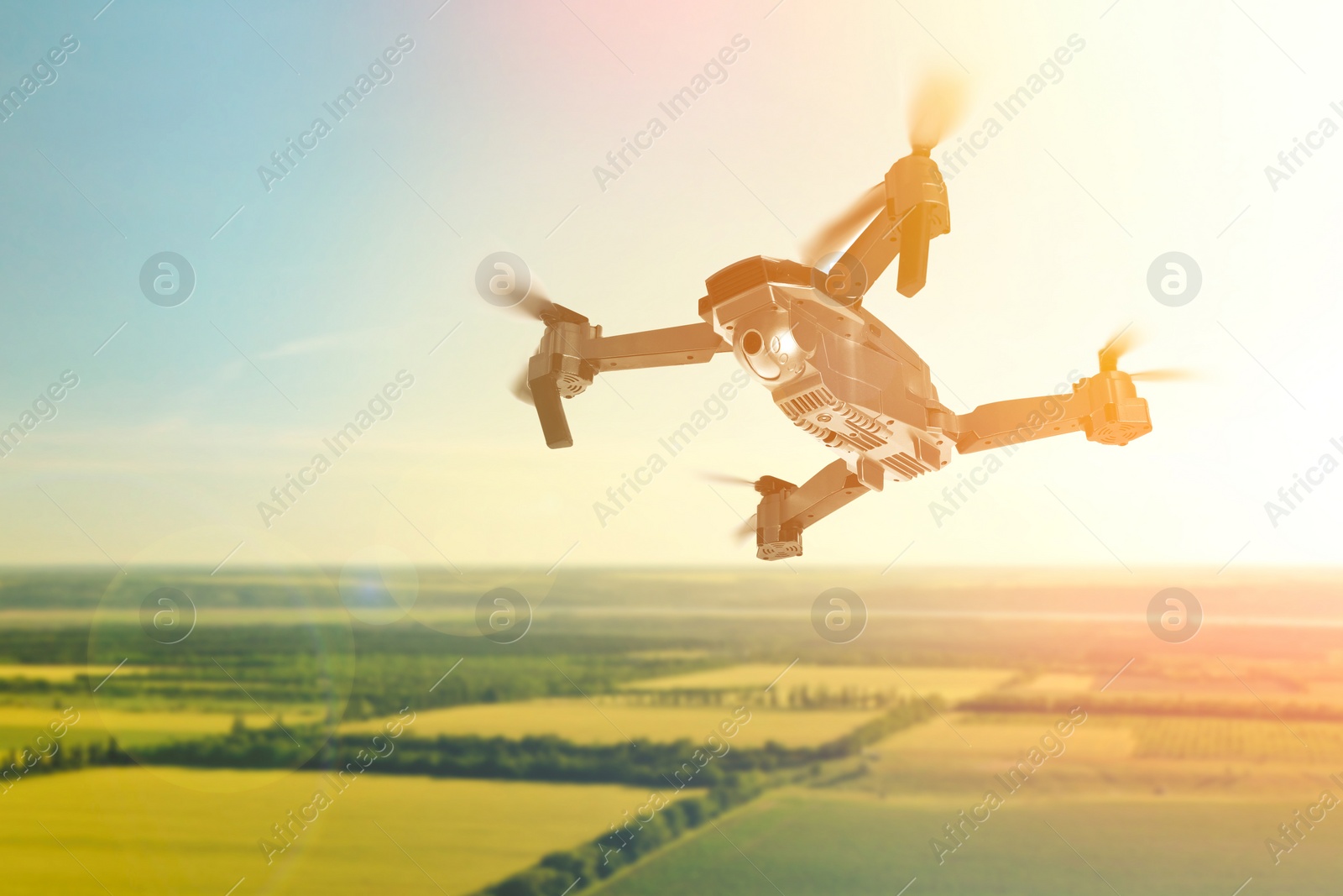 Image of Modern drone flying over fields on sunny day. Aerial survey