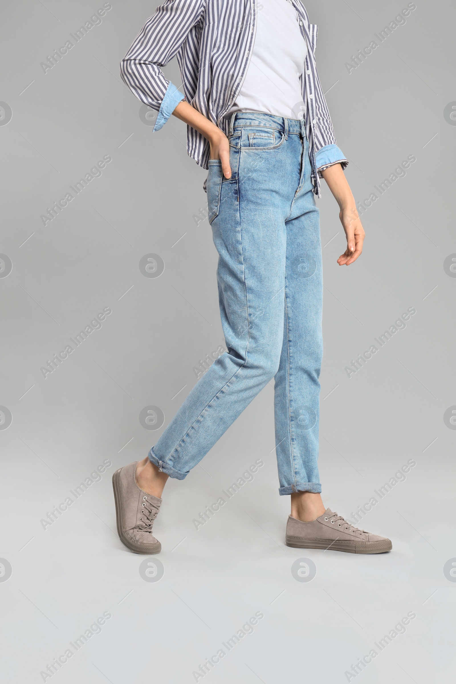 Photo of Young woman in stylish jeans on grey background, closeup