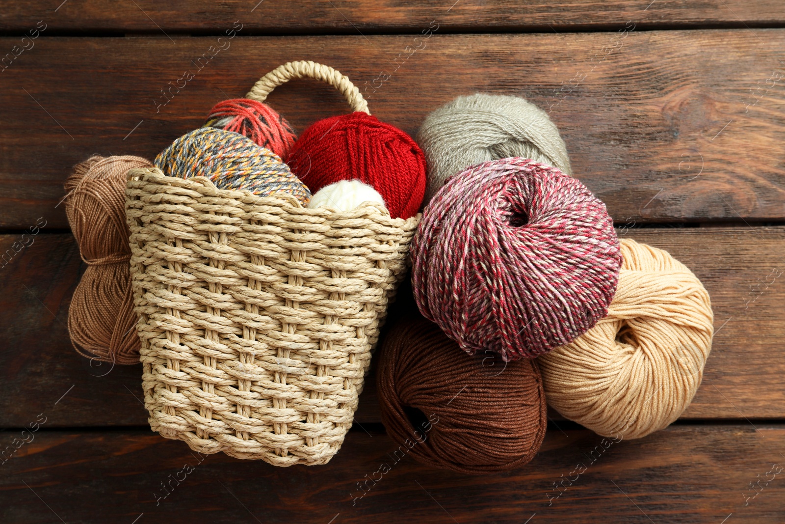 Photo of Soft woolen yarns on wooden table, flat lay